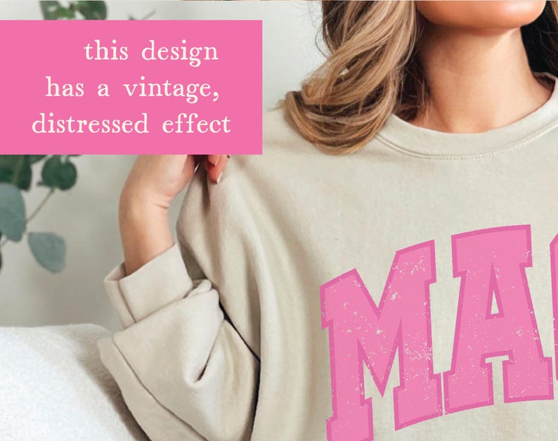 May include: A light beige sweatshirt with a pink vintage-style graphic that says "MA" with a distressed effect. The design has a vintage, distressed effect.