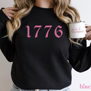 May include: Black sweatshirt with a pink 1776 graphic and the text "pink patriot" on a white mug.