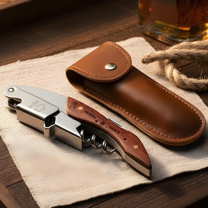 May include: A stainless steel and wood corkscrew with the names "Dustin" and "Nancy" engraved on the wooden handle. The corkscrew is next to a brown leather case. The word "PUSH" and an arrow are printed on the metal.