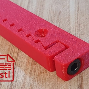 Può includere: Un oggetto rosso brillante stampato in 3D con una serie di intagli a gradini e un foro circolare. Una vite esagonale nera è visibile a un'estremità. L'immagine include anche un'icona del file .stl.