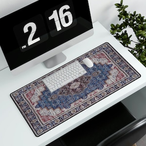May include: A blue and red patterned desk mat with a white computer keyboard and a white computer mouse on top. The desk mat is on a white desk.