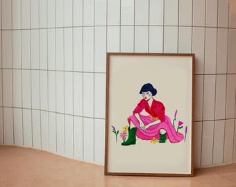 May include: A framed illustration of a woman in a pink skirt and red shirt sitting in a field of flowers. The woman has short black hair and is wearing green boots.