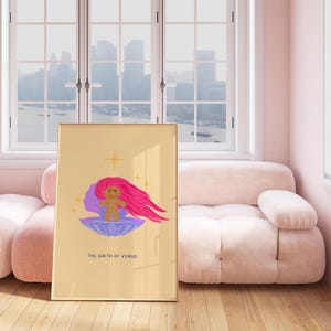 Op de afbeelding: Een digitale illustratie van een trollpop met roze haar die op een paarse schelp zit met een gouden ster erboven. De tekst "THE BIRTH OF VENUS" staat onder de trollpop. De illustratie is ingelijst en hangt aan een muur in een kamer met een roze bank en ramen.