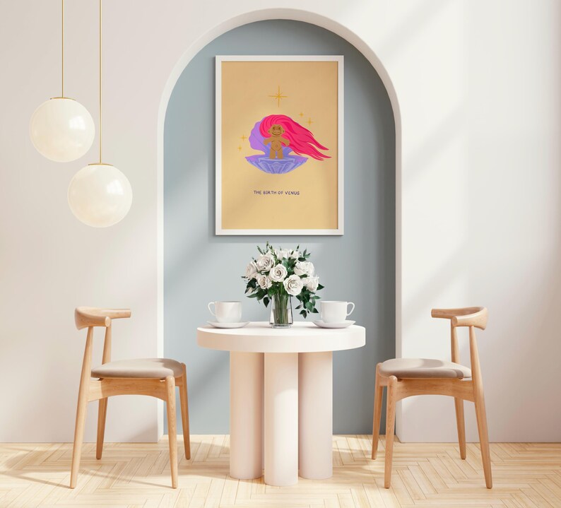 Op de afbeelding: Een gouden ingelijste print met een gele achtergrond en een paarse en roze illustratie van een baby in een schelp. De tekst "The Birth of Venus" staat onder de illustratie.