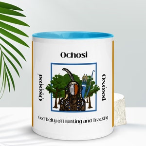 May include: White ceramic mug with a blue interior and a gold-coloured vertical stripe. The mug features the word "Ochosi" and an illustration of a deity with a bow and arrow, with the text "God Deity of Hunting and Tracking".