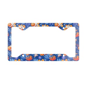 May include: A blue license plate frame featuring a repeating pattern of orange and white clownfish, coral, and seaweed. The frame has a rectangular shape with cutouts for the plate and mounting hardware.