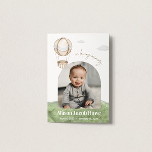 Op de afbeelding: Een witte kaart met een aquarel-illustratie van een luchtballon en wolken. De kaart heeft een foto van een babyjongen in een grijze outfit. De tekst op de kaart luidt "In liefdevolle herinnering, Mason Jacob Howe, 4 april 2023 - 11 januari 2024."