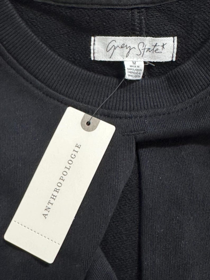 May include: A black sweatshirt with a white tag that says "Grey State" and a white tag that says "Anthropologie".