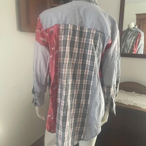 Pode incluir: Uma camisa de manga comprida feita de tecido patchwork. A camisa &eacute; azul, branca, vermelha e preta com um padr&atilde;o floral. A camisa est&aacute; em um manequim.