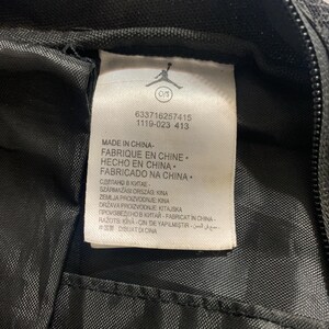 K&ouml;nnte beinhalten: Ein wei&szlig;es Etikett mit schwarzem Text auf schwarzem Hintergrund. Das Etikett lautet "Made in China - Fabrique en Chine - Hecho en China - Fabricado na China" und enth&auml;lt eine Liste von L&auml;ndern und Sprachen mit dem Text "Made in China".