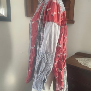 Pode incluir: Uma camisa de bot&otilde;es de manga comprida com um design de patchwork. A camisa &eacute; feita de diferentes tecidos, incluindo xadrez, listras e padr&otilde;es florais. A camisa &eacute; vermelha, azul e branca.