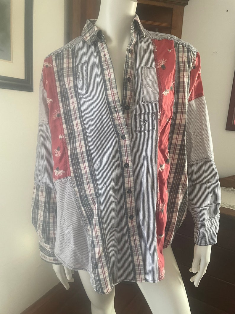 Pode incluir: Uma camisa de manga comprida com bot&otilde;es e design de patchwork. A camisa &eacute; feita de uma variedade de tecidos, incluindo xadrez, listras e cores s&oacute;lidas. A camisa tem um caimento solto e uma gola.