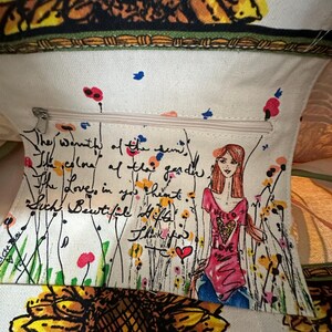 Peut inclure: Sac fourre-tout cr&egrave;me avec un motif de tournesol et un motif floral. L'int&eacute;rieur comporte une poche zipp&eacute;e avec un message manuscrit et un dessin d'une femme en chemise rose et jean bleu.