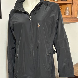 May include: A black zip-up jacket with a stand-up collar and a zippered pocket on the left side.