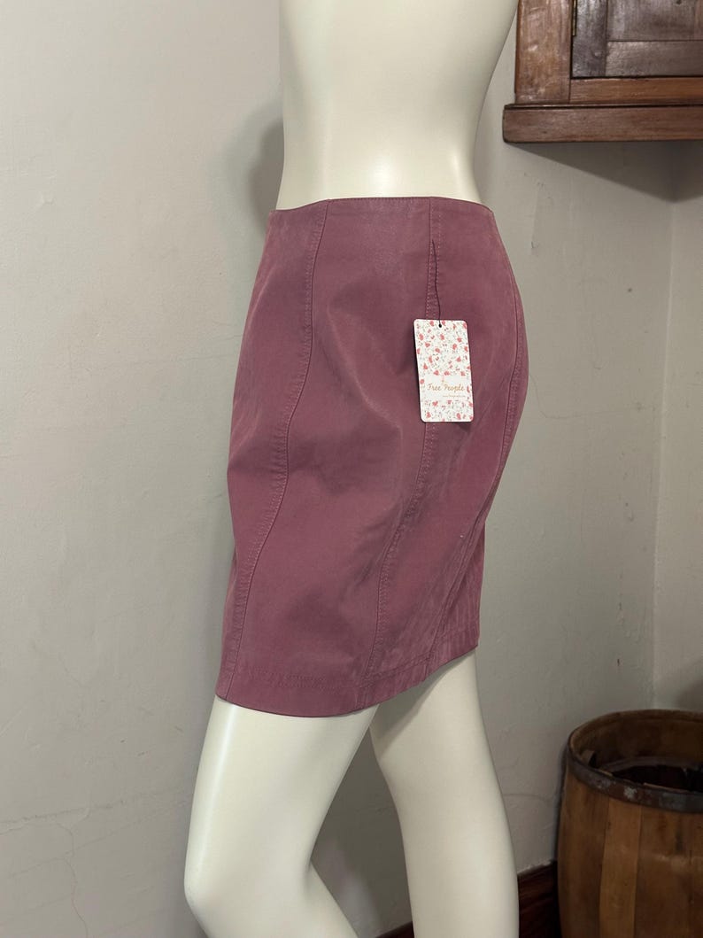 Op de afbeelding: Een stoffige roze minirok met een getailleerd silhouet. De rok heeft verticale naden en een klein label met de tekst "Free People". De rok wordt op een mannequin getoond.
