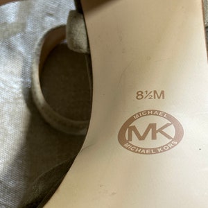 Pu&ograve; includere: Primo piano dell'interno di una scarpa marrone chiaro con la taglia 8 1/2 M e il logo Michael Kors stampato sulla soletta.