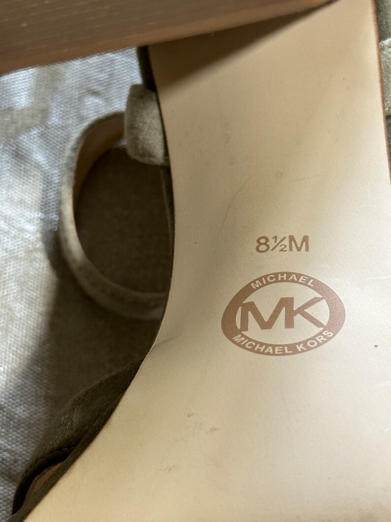 Pu&ograve; includere: Primo piano dell'interno di una scarpa marrone chiaro con la taglia 8 1/2 M e il logo Michael Kors stampato sulla soletta.