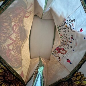 Peut inclure: Vue int&eacute;rieure d'un sac fourre-tout avec un imprim&eacute; tournesol et "LOVE". Le sac a une bordure verte et une petite poche zipp&eacute;e avec une illustration color&eacute;e. L'int&eacute;rieur est de couleur cr&egrave;me.