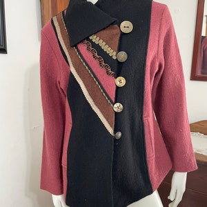 May include: A black and burgundy wool jacket with a unique asymmetrical design. The jacket features a large collar, decorative trim, and multiple large buttons.