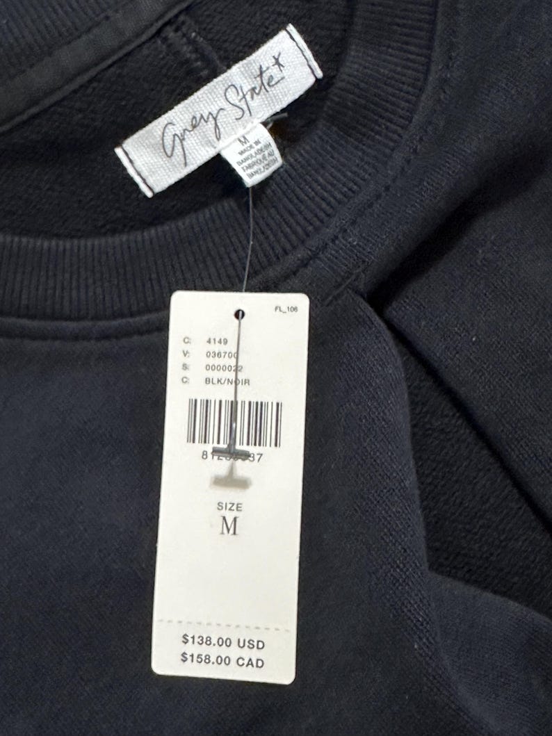 May include: Black sweatshirt with a white tag that says "Grey State" and a price tag that says "$138.00 USD $158.00 CAD". The tag also says "Size M" and has a barcode.