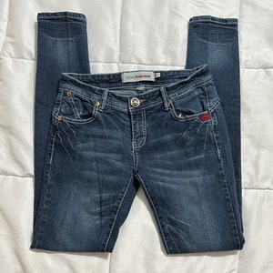 May include: Dark blue skinny jeans with a red and white logo that says "Rock & Republic" on the back pocket.