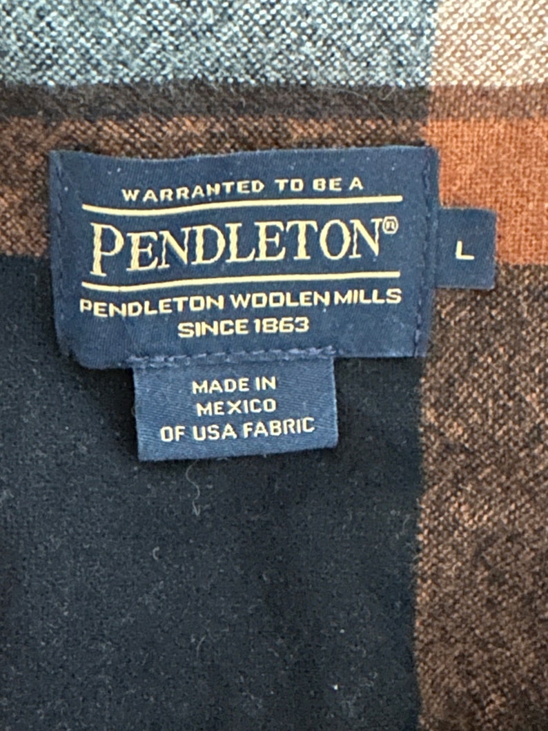 May include: A black and brown plaid Pendleton shirt with a label that reads "WARRANTED TO BE A PENDLETON&reg; PENDLETON WOOLEN MILLS SINCE 1863 MADE IN MEXICO OF USA FABRIC" and a size label that reads "L".