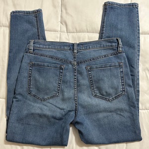 May include: A pair of blue denim jeans with a classic five-pocket style. The jeans have a straight leg and a mid-rise waist.