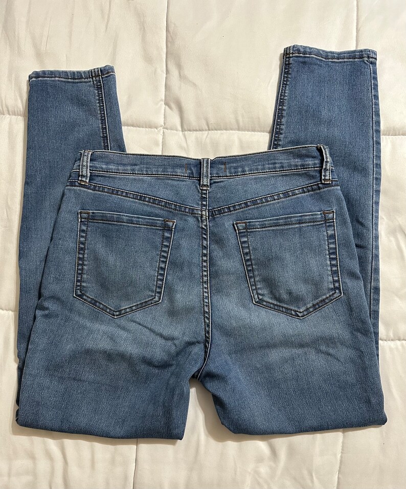 May include: A pair of blue denim jeans with a classic five-pocket style. The jeans have a straight leg and a mid-rise waist.