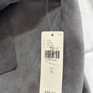 Pu&ograve; includere: Un blazer grigio con un'etichetta attaccata. L'etichetta include la taglia "S" e il numero "49873748". Il blazer &egrave; realizzato in un materiale morbido e ha un design classico.