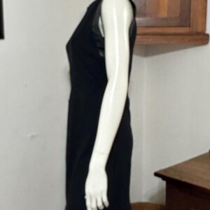 May include: A black sleeveless dress with a sheer mesh panel on the bodice. The dress is fitted and has a straight skirt.