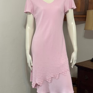 May include: A light pink dress with a V-neck and short, flutter sleeves. The dress features a scalloped hemline with beaded embellishments. The dress is displayed on a mannequin.