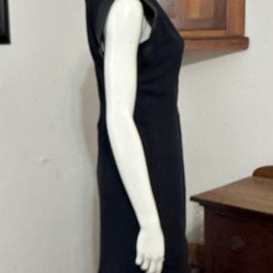 May include: A black sleeveless dress with a leather detail on the shoulders. The dress is fitted and has a straight skirt.