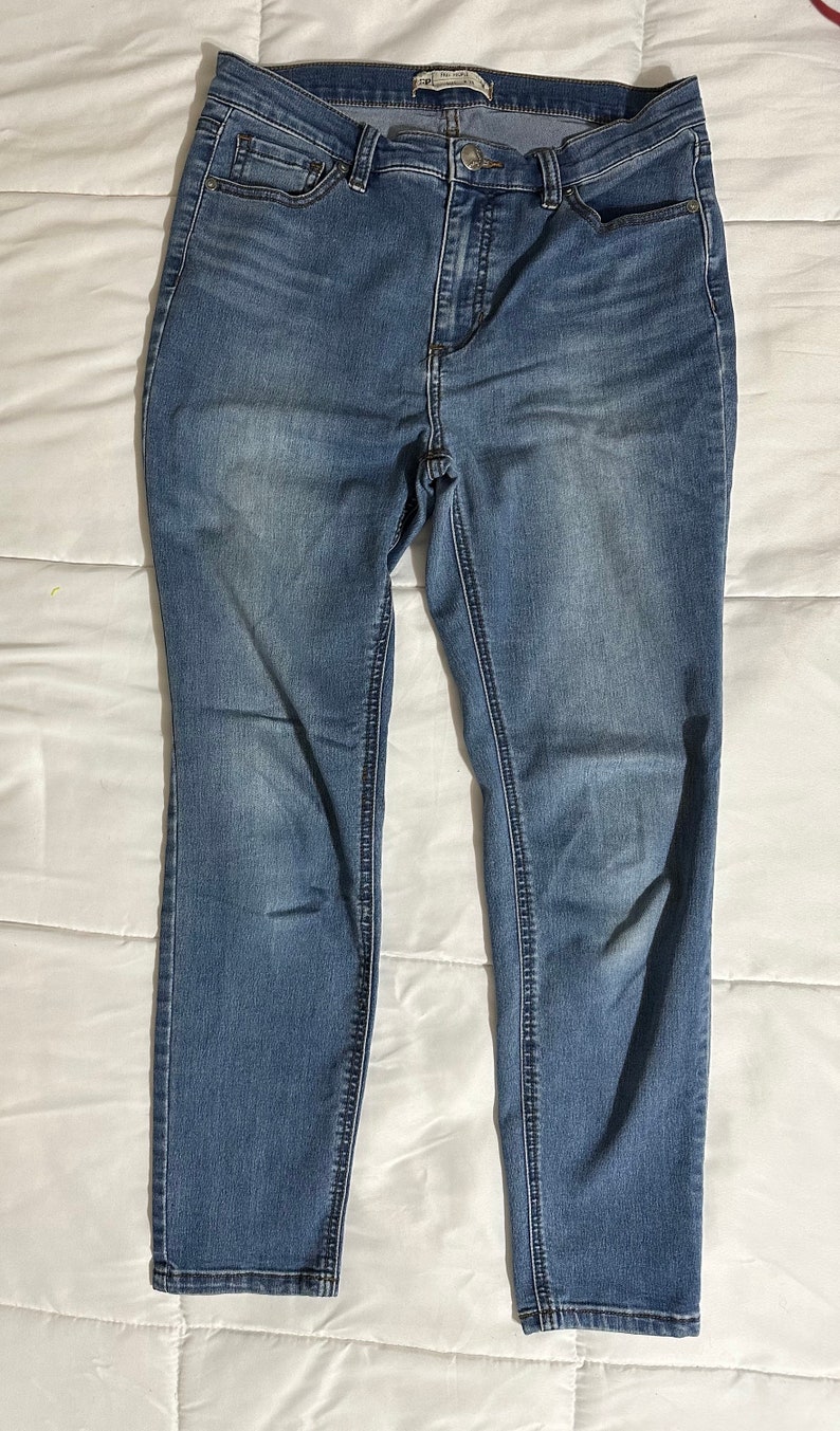 May include: A pair of blue denim jeans with a faded wash. The jeans have a slim fit and a mid-rise waist.