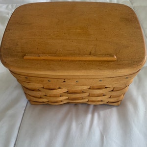 May include: A natural wood woven basket with a hinged lid. The lid has a small wooden latch.