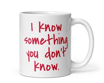 May include: White ceramic mug with a curved handle. The mug features the red text, "I know something you don't know."