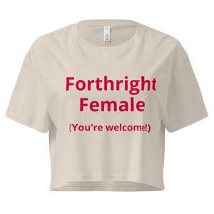 May include: A cream-colored crop top with the words "Forthright Female" in red, with the phrase "(You're welcome!)" below. The shirt has short sleeves and a crew neck.