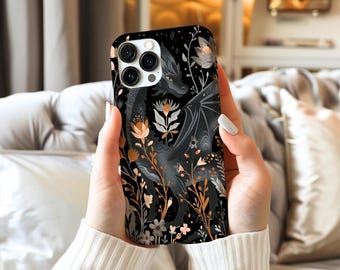 May include: Black phone case featuring a dragon illustration with floral accents in shades of peach, gray, and gold. The dragon has detailed wings and is surrounded by stylized flowers and foliage. The case has a glossy finish.