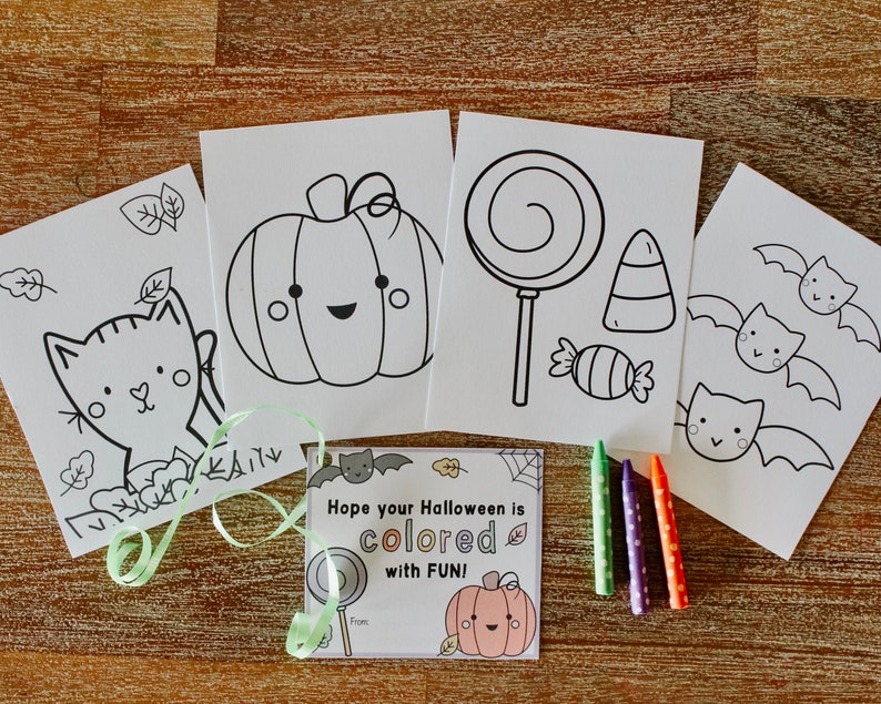 May include: Four black and white coloring pages featuring a pumpkin, a lollipop, a candy cane, bats, and a cat. The pages are on a wooden surface with green and purple crayons.