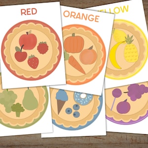 May include: Six colorful plates with different fruits and vegetables on each. The plates are labeled with the colors red, orange, yellow, green, blue, and purple.