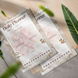 Puede incluir: Dos p&aacute;ginas de planificador diario imprimibles con un dise&ntilde;o floral. Las p&aacute;ginas incluyen secciones para listas de tareas, recordatorios, prioridades, objetivos y un rastreador de agua.