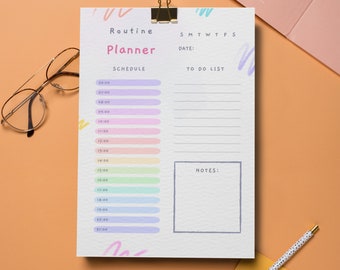 Puede incluir: Un planificador diario blanco con una sección de horario de color arcoíris y una sección de lista de tareas. El planificador tiene las palabras "Routine Planner" en la parte superior y los días de la semana abreviados en la parte superior derecha.