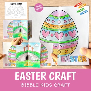 Peut inclure: Un kit d'artisanat de Pâques coloré avec une surprise pliante. Le kit comprend un grand œuf décoré avec des cœurs et des cercles, et une scène avec des croix et le texte "Il est ressuscité !" Les mots "Joyeuses" et "Pâques" sont également visibles.