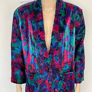 Könnte beinhalten: Ein farbenfroher Blazer mit abstraktem Druck, einem einzigen Knopfverschluss und zwei Taschen. Der Blazer ist aus seidenartigem Stoff gefertigt und hat eine lockere Passform.