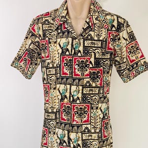 Peut inclure: Chemise à manches courtes avec un motif répété de figures rouges, noires et turquoise sur fond crème. La chemise a un col classique et une coupe décontractée, adaptée aux tenues décontractées. Le motif présente des motifs d'inspiration tribale.