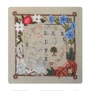 May include: A cross-stitch sampler with a beige background, featuring a floral and alphabet design. The sampler includes red, white, and blue flowers, a tree, and the letters of the alphabet. The border is a dark brown.