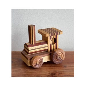 May include: A wooden toy train with a striped design in shades of brown, red, and white. The train has a chimney, a caboose, and wheels.