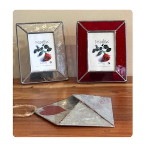 May include: Two rectangular picture frames, one clear and one red, with a photo of a rose and the word "Possibilities". Below, a metal envelope with a red heart detail hangs by a twine string.