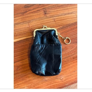 May include: A black leather coin purse with a gold chain and clasp. The purse has a quilted design.