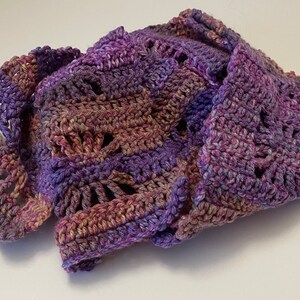 May include: A crocheted scarf in shades of purple, pink, and brown with a lacy pattern.