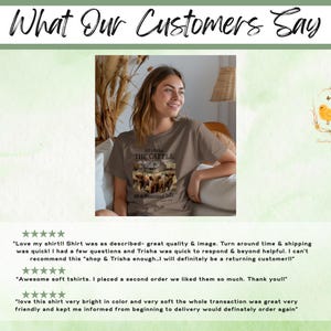 May include: A taupe short-sleeved t-shirt featuring a graphic print of a herd of cattle in a field with a barn in the background. The text on the shirt reads: HE OWNS THE CATTLE ON A THOUSAND HILLS. The shirt has a crew neckline and a relaxed fit.